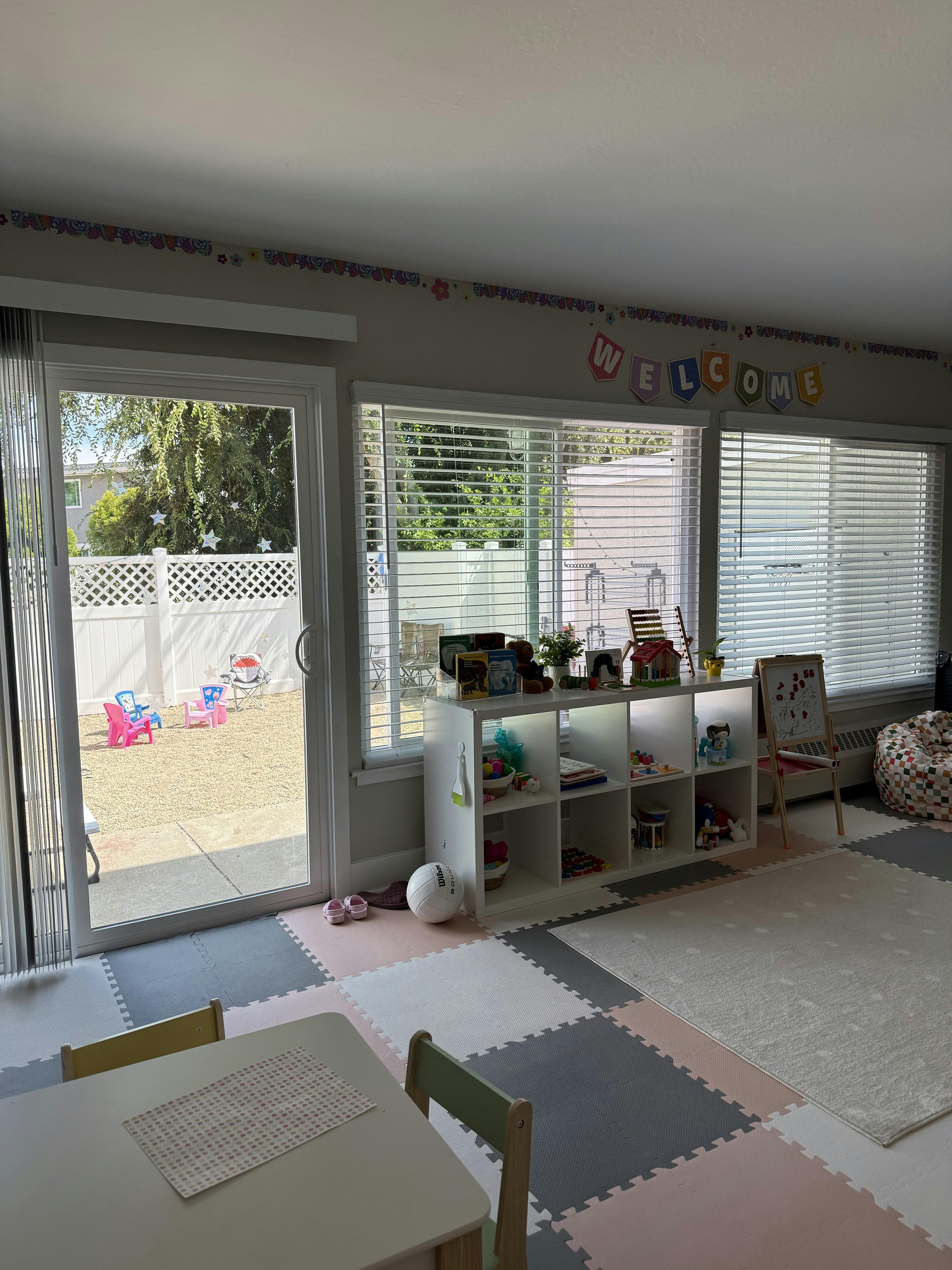 Playroom with children furniture and toys on a shelf overlooking a backyard