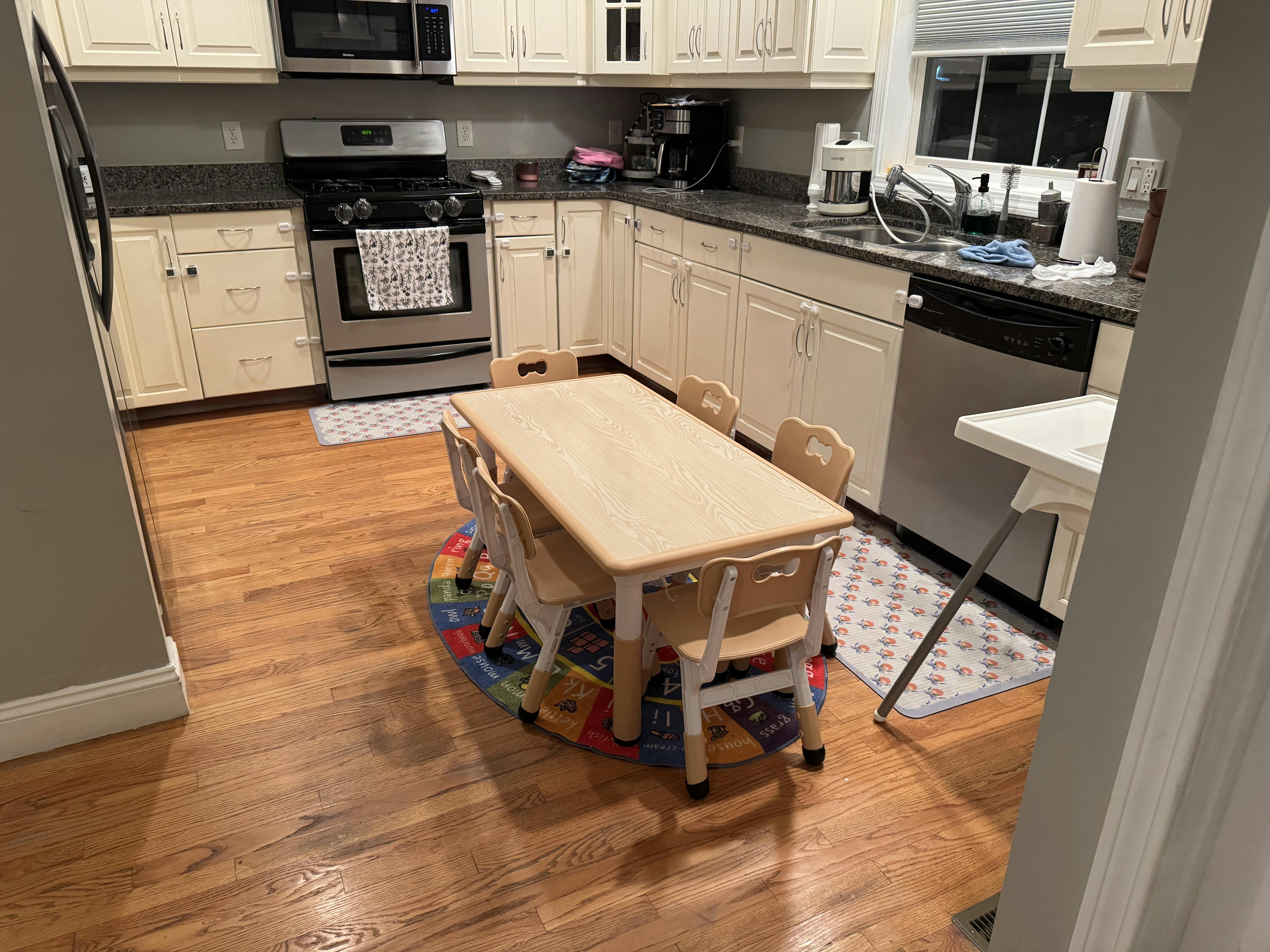 kitchen with wooden floors, white cabinets, and a child's table and chairs