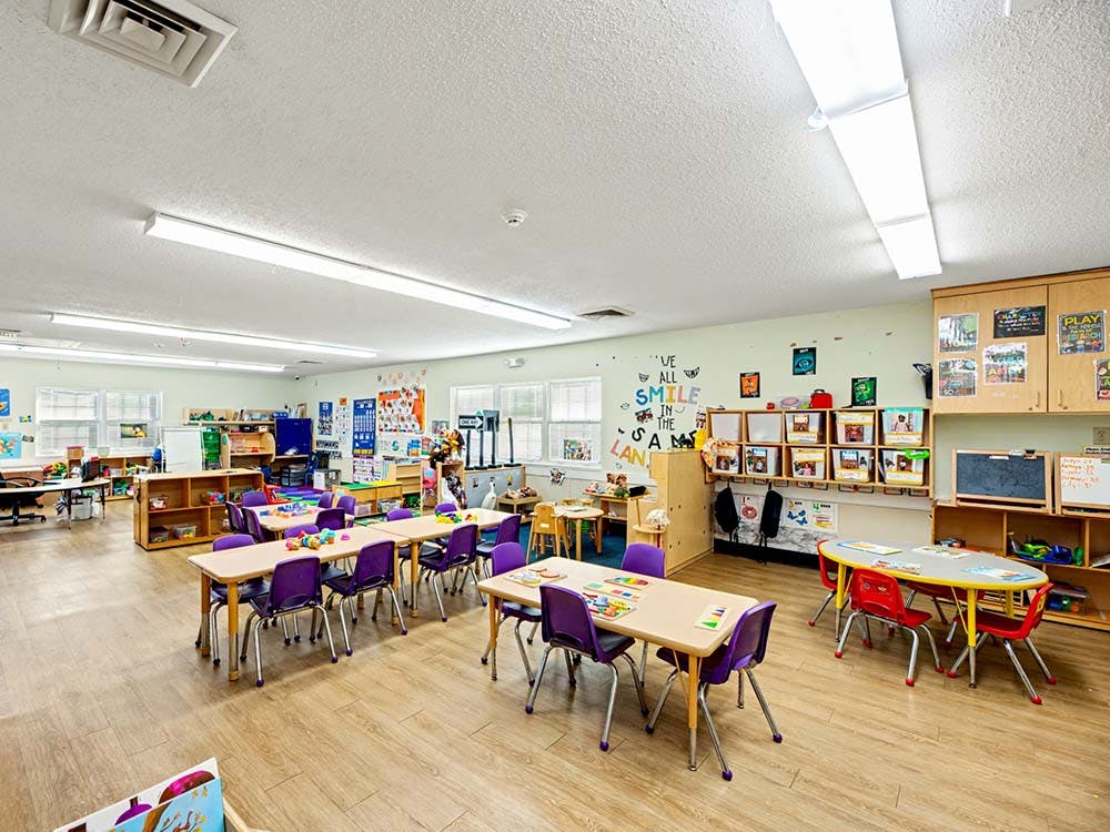 Classroom with small tables and chairs, shelves, and learning materials