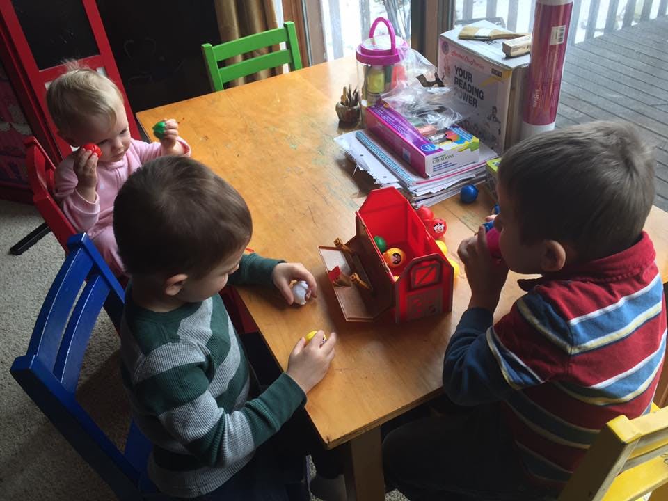 Three children sitting at a table playing with toys