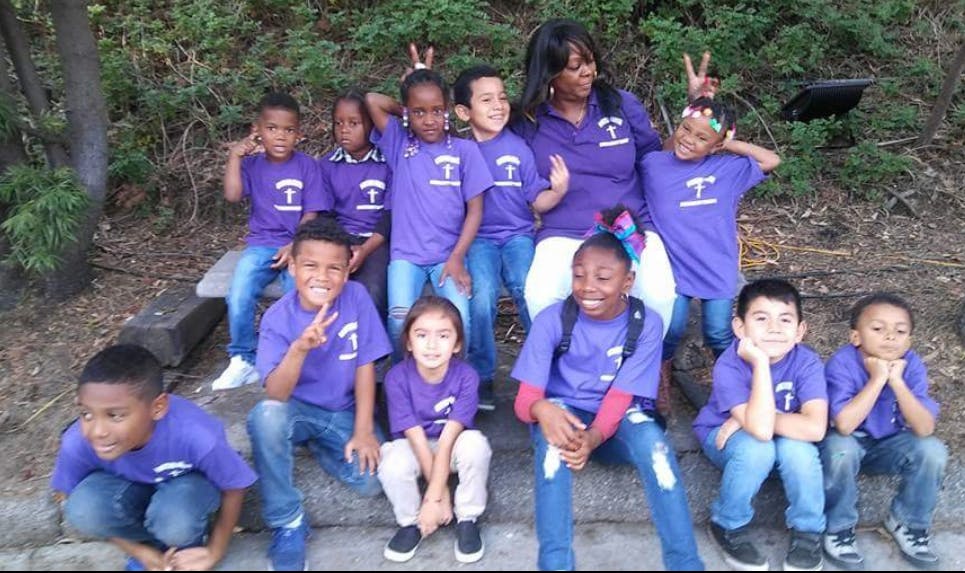 Adult and children in purple shirts posing for a photo outdoors group photo
