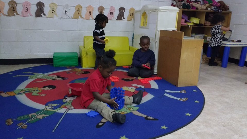 Children playing on a rug in a classroom