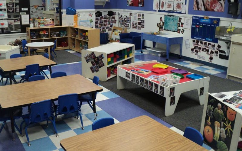 An empty early childhood classroom with multiple activity stations and tables
