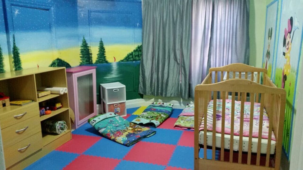 Nursery room with crib, colorful floor mats, and mural