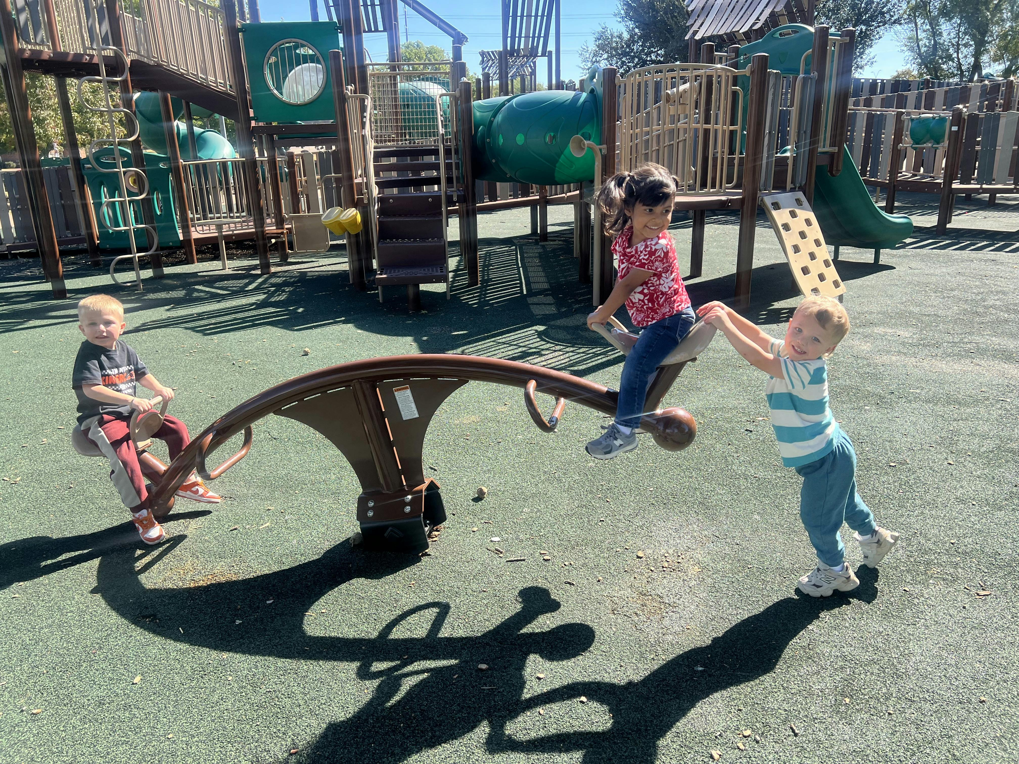 Three children playing on a seesaw at a playground