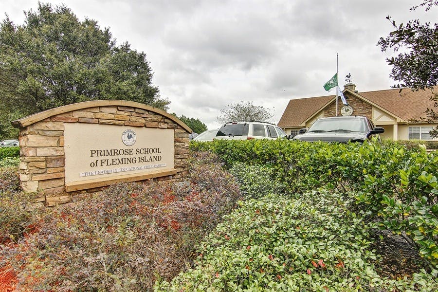 Stone sign for Primrose School of Fleming Island with building and cars in background
