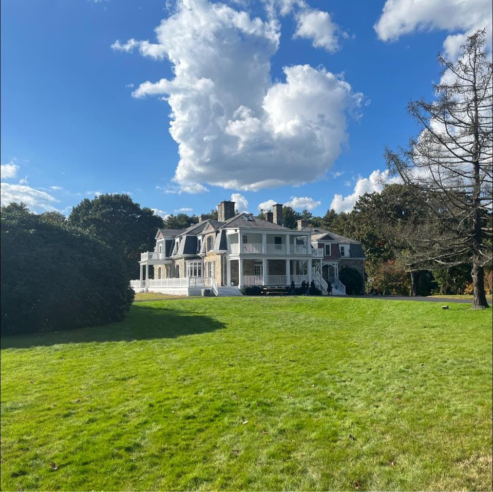 large stone mansion with multiple balconies and a vast green lawn
