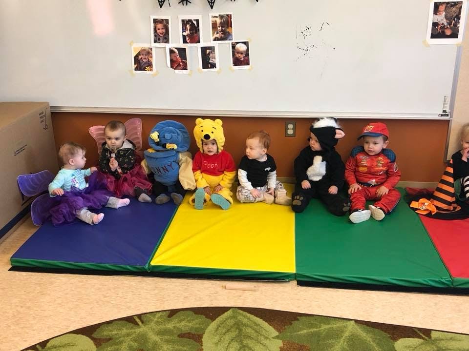 Children in costumes sitting on colorful mats