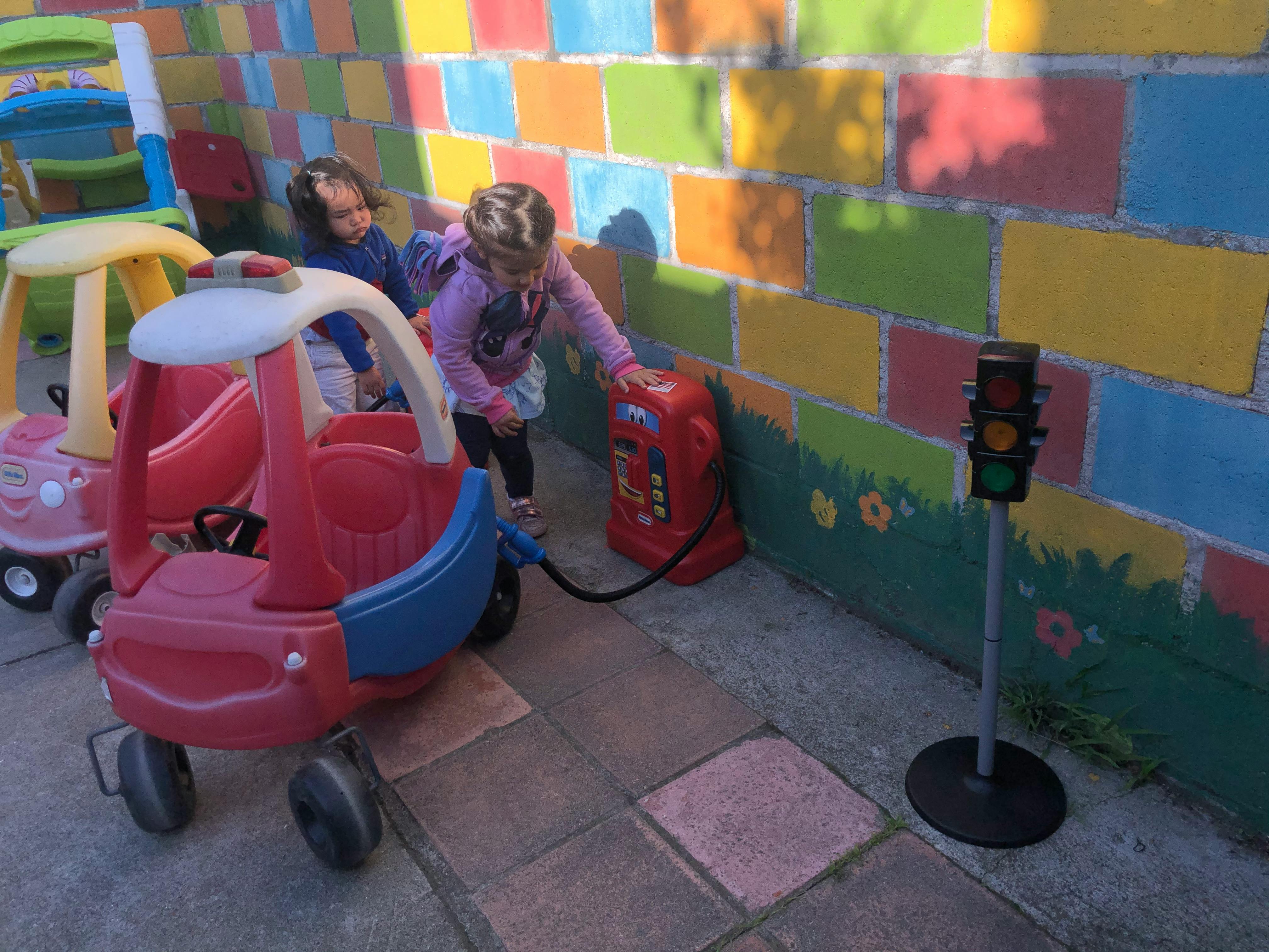 Two children playing with a toy car and gas pump