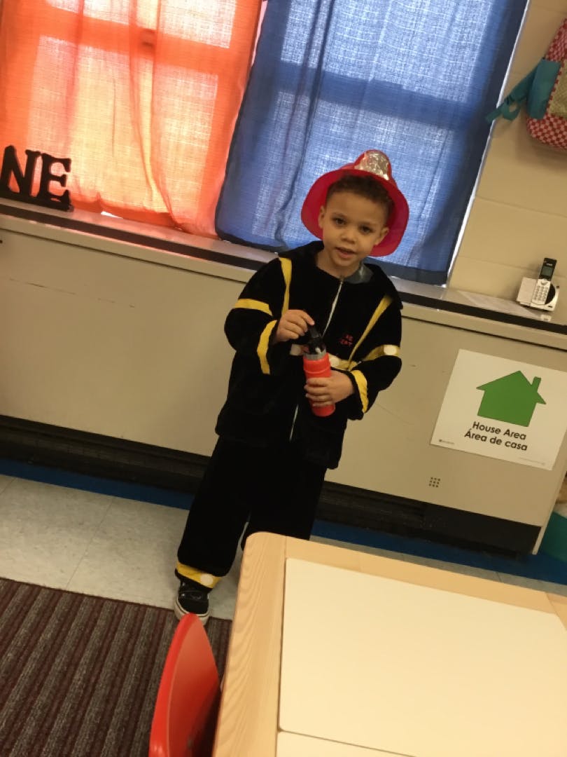 Child in firefighter costume holding a water bottle