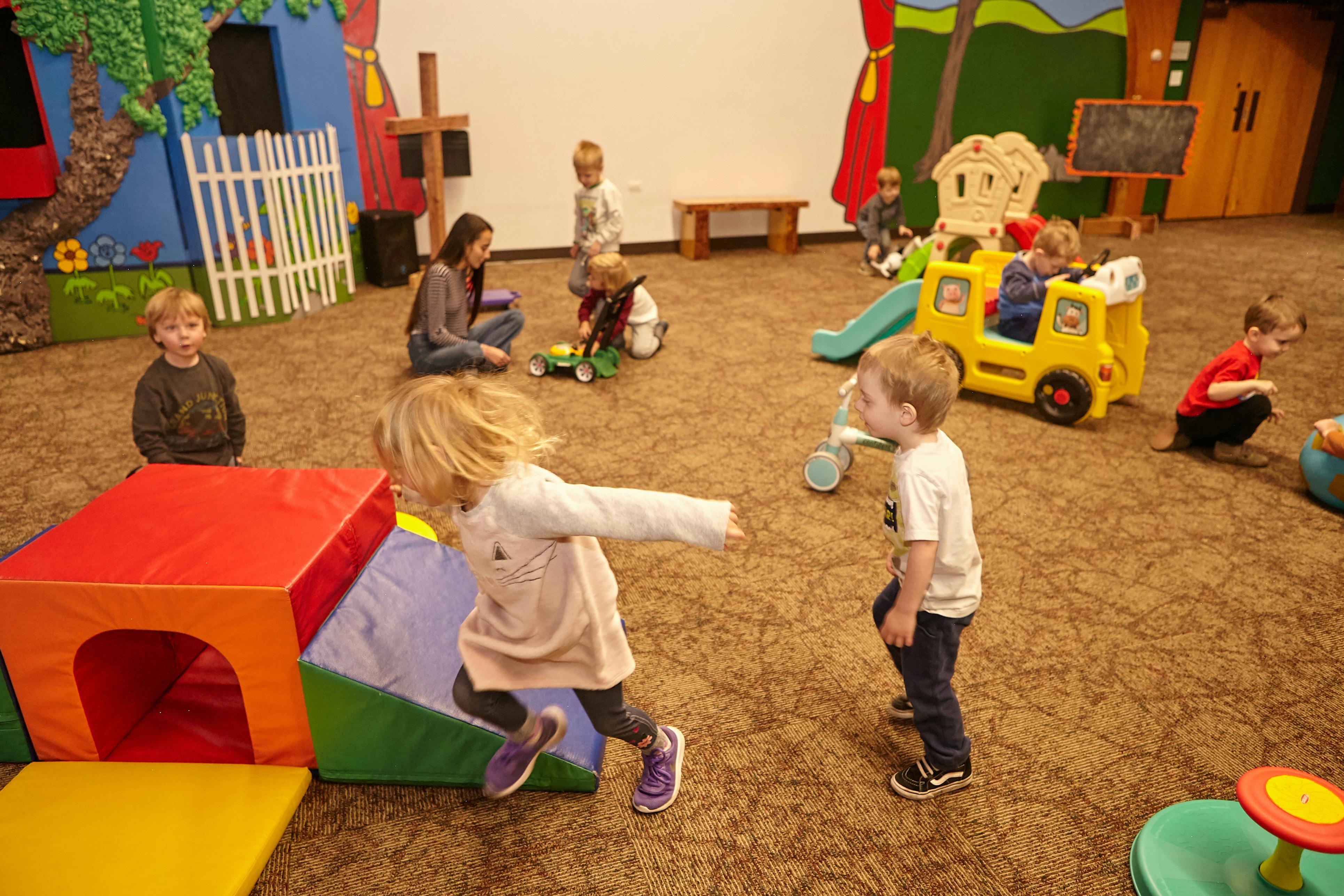 Children playing in a room with soft play equipment and toys