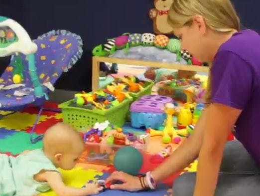 Person and child playing with toys on a colorful mat