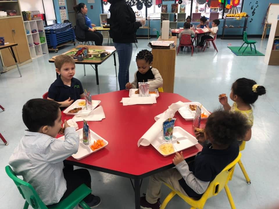 Children eating at a red table in a classroom