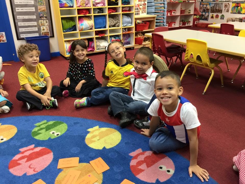 Five children sitting on a rug in a classroom