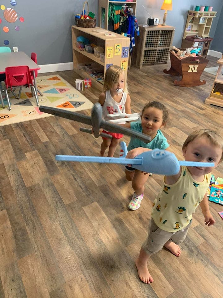 Three children playing with toy airplanes in a room