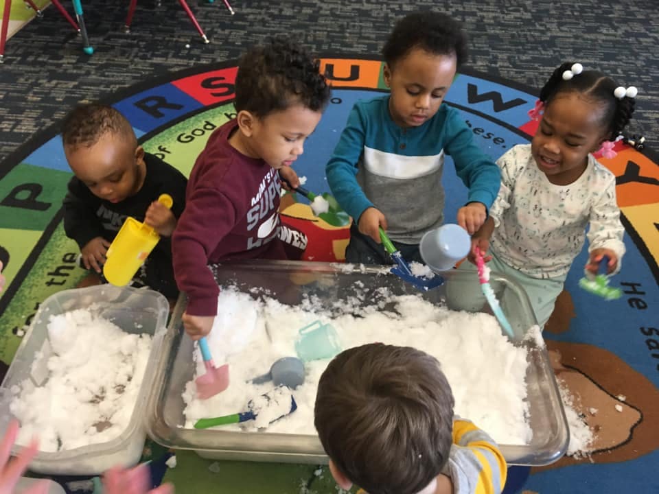 Children playing with white sensory material and scoops