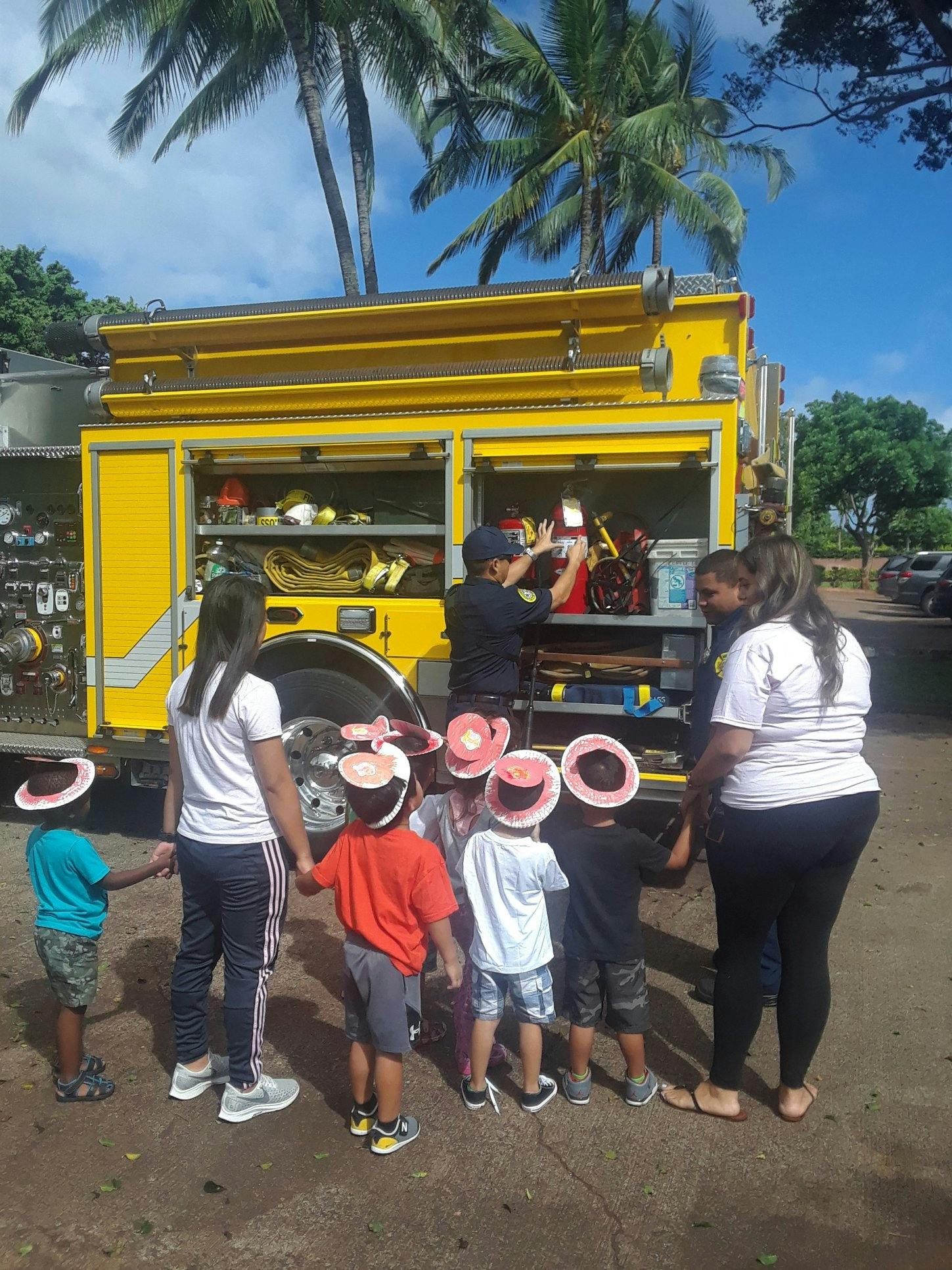 People and children gathered around a yellow fire truck