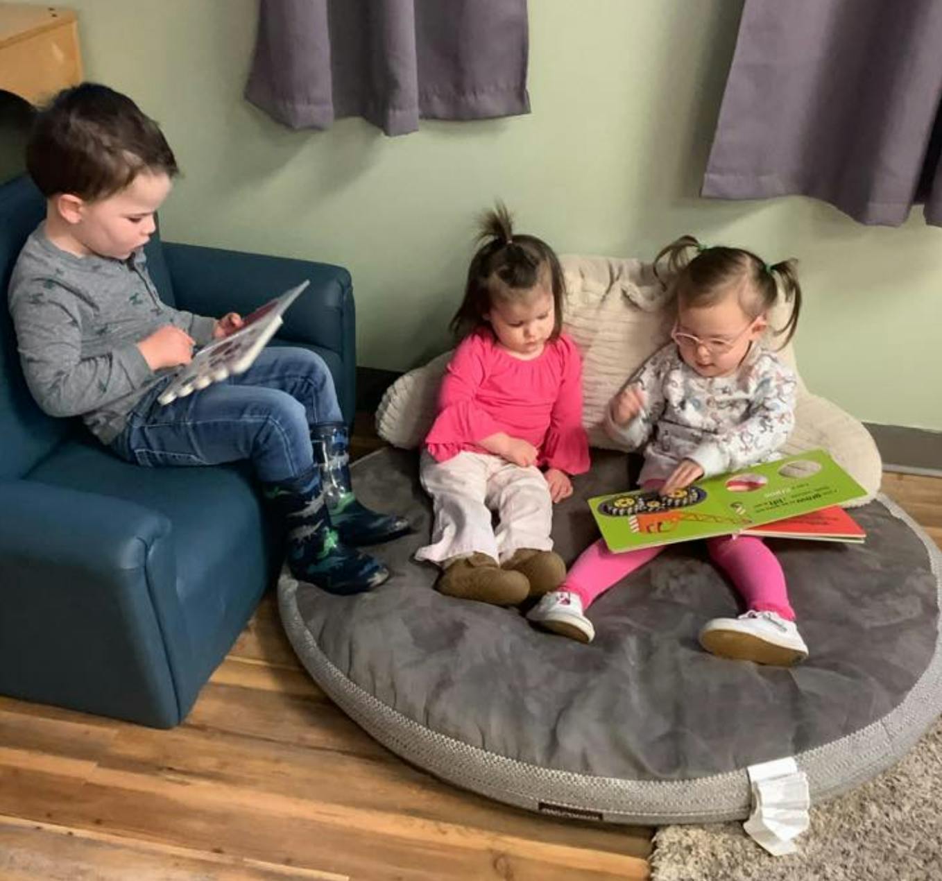 Three children reading books in a room