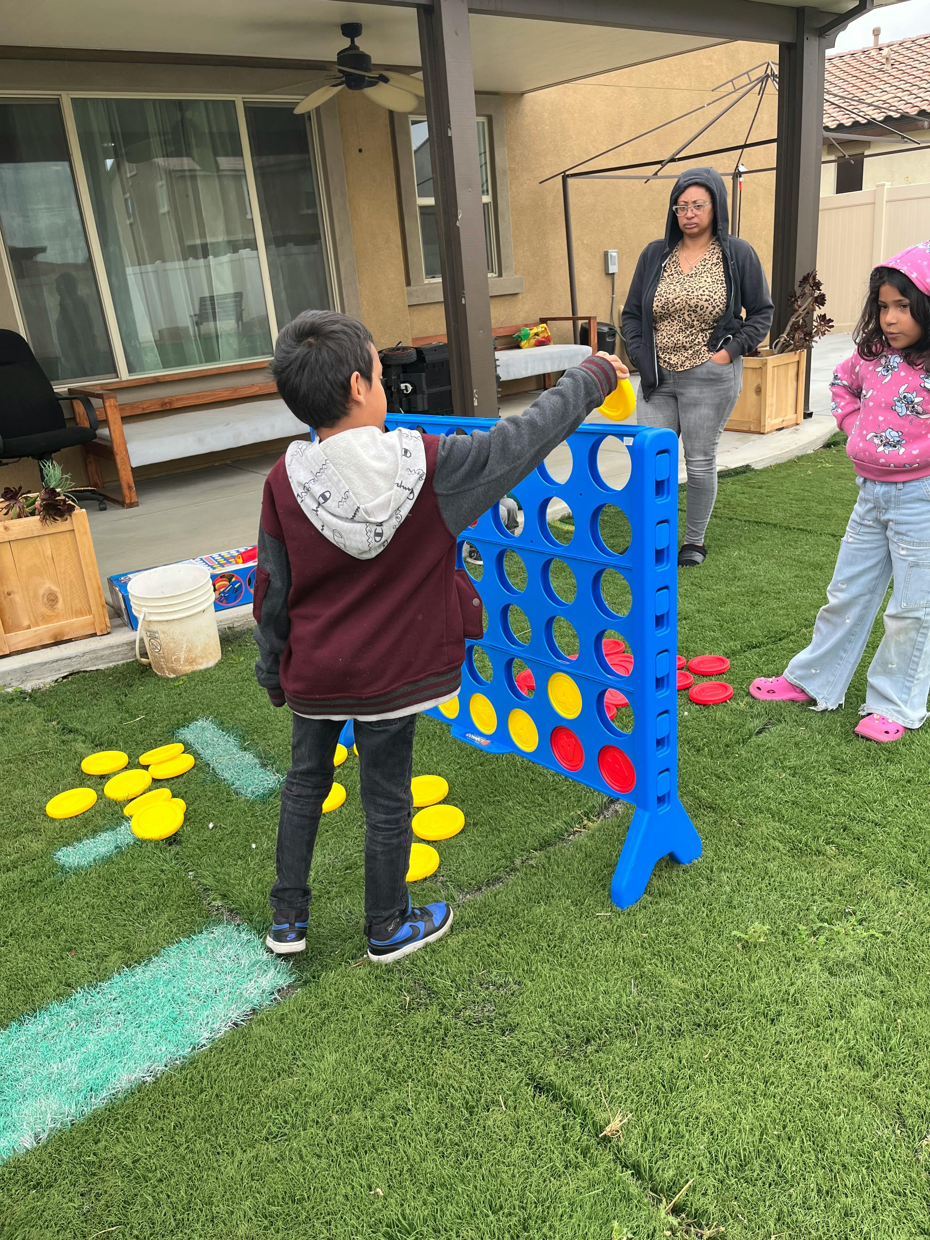Child playing a large Connect Four game outdoors