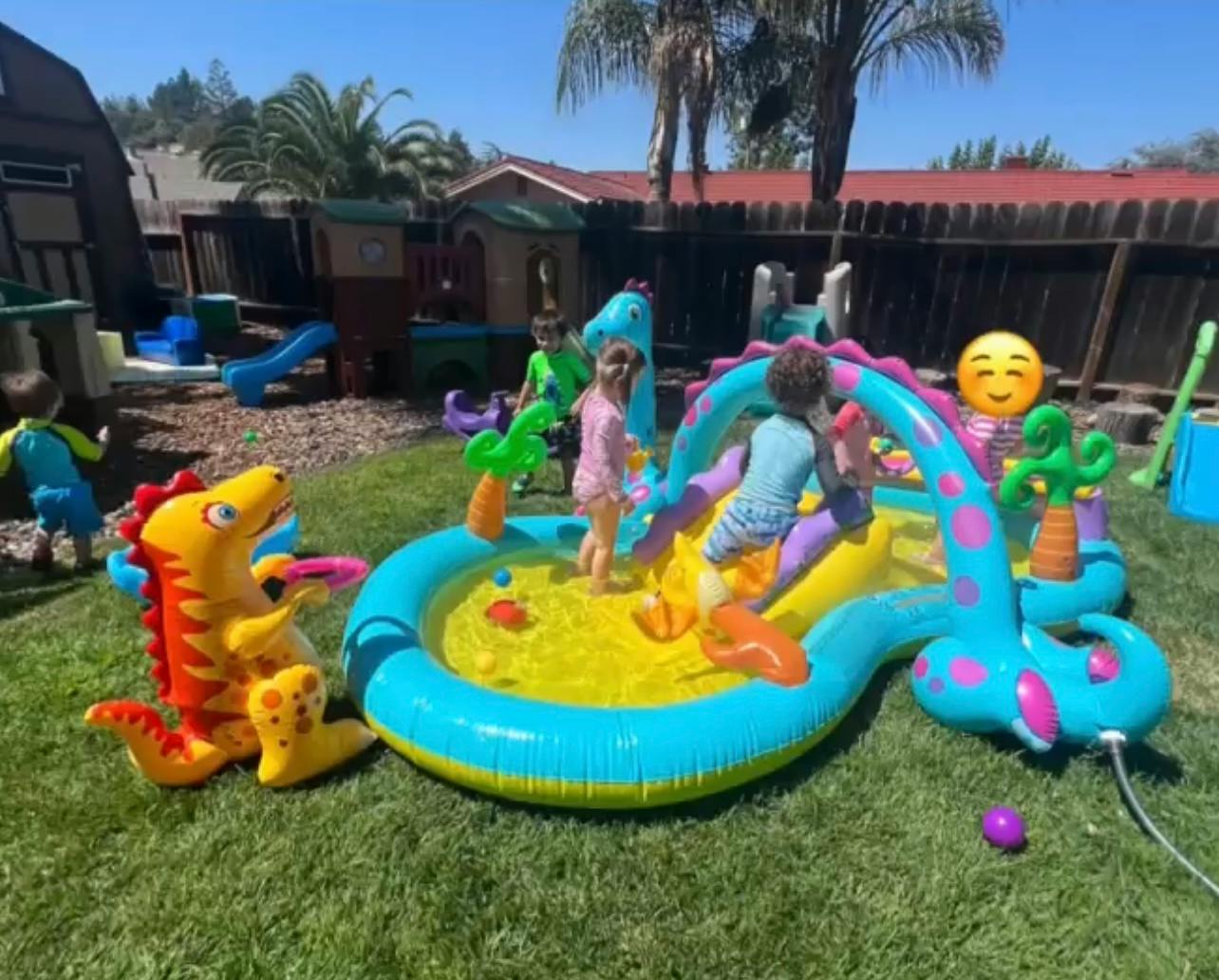 Children playing in an inflatable dinosaur-themed pool