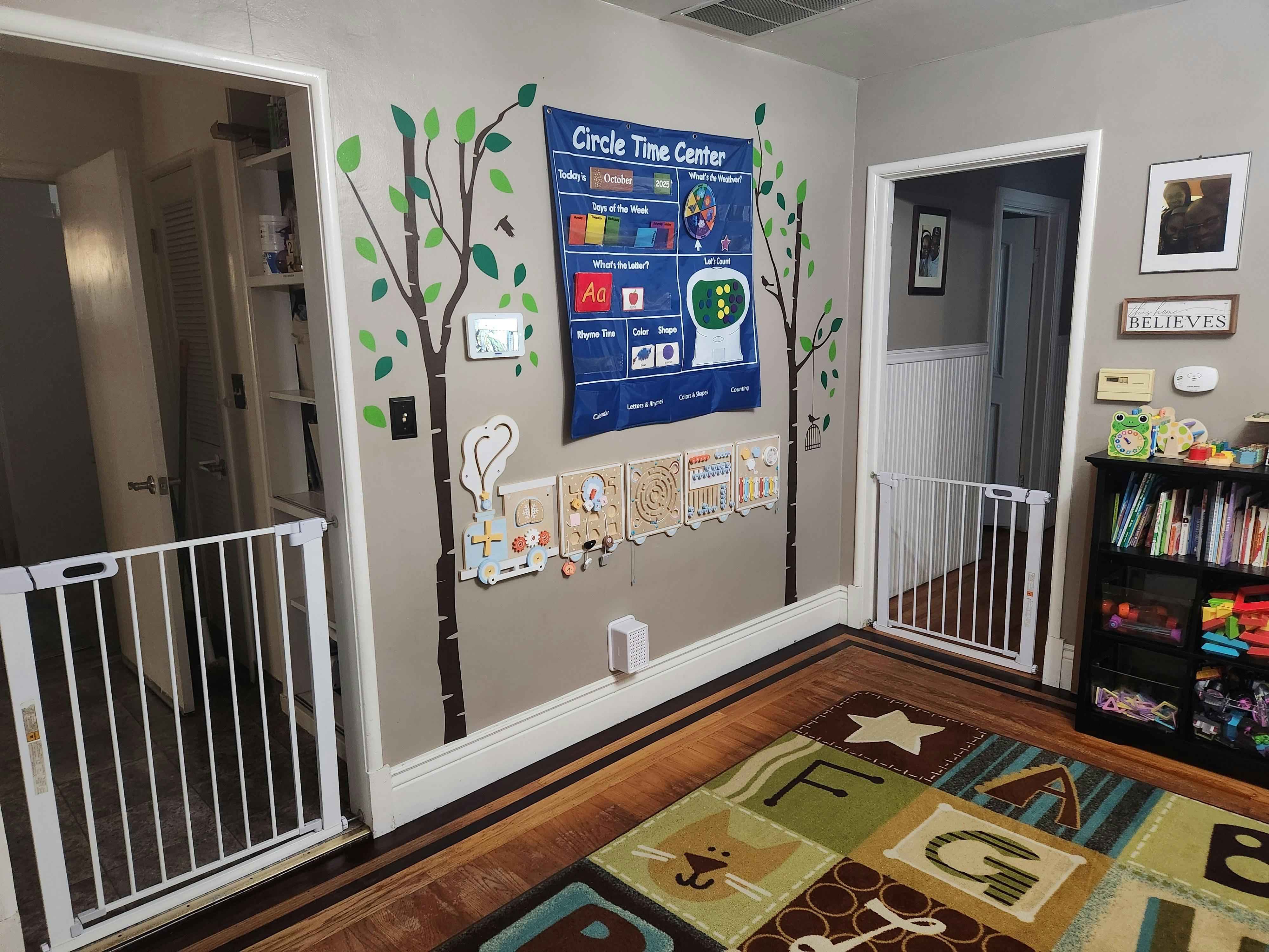 Playroom with a "Circle Time Center" chart, tree decals, and baby gates
