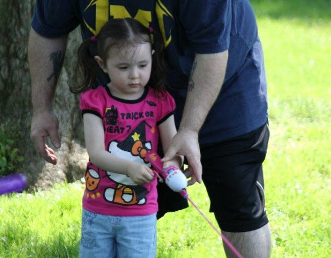 Child holding a toy with a person standing next to them