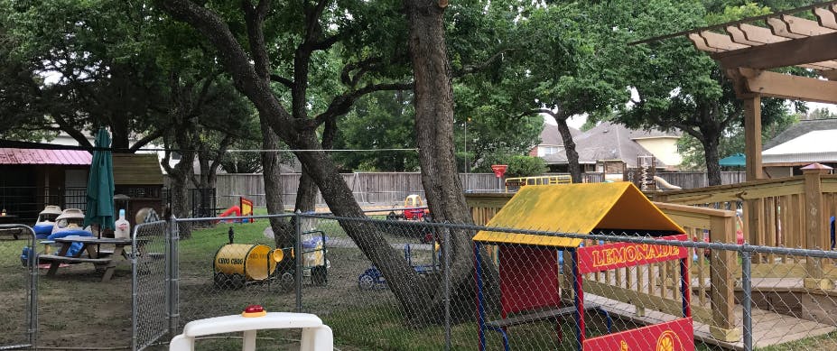 Outdoor playground with a wooden deck, playhouse, and picnic table
