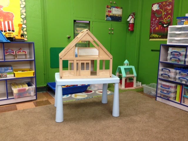 Wooden dollhouse on a white table in a classroom