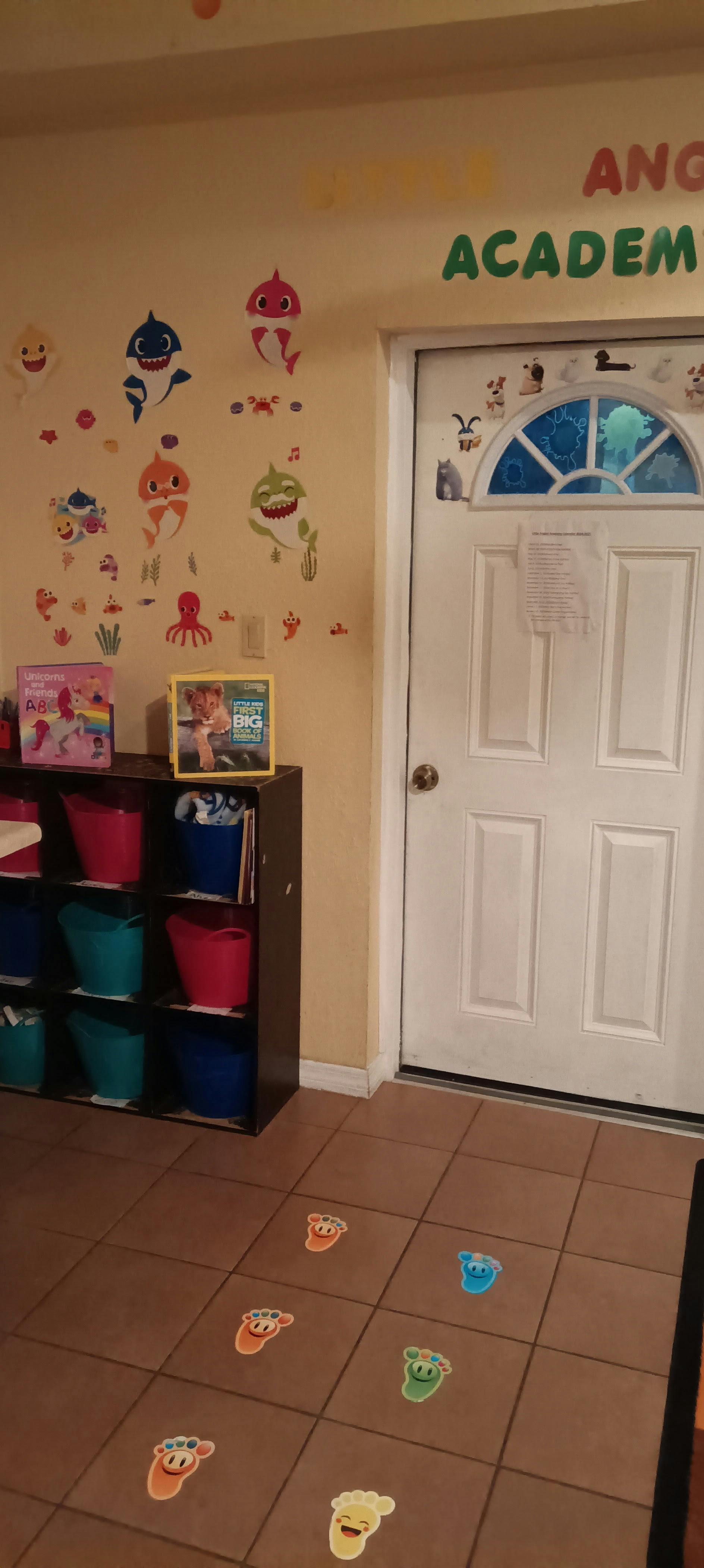 Room with 'Baby Shark' wall decals, a storage shelf, and footprint stickers on the floor