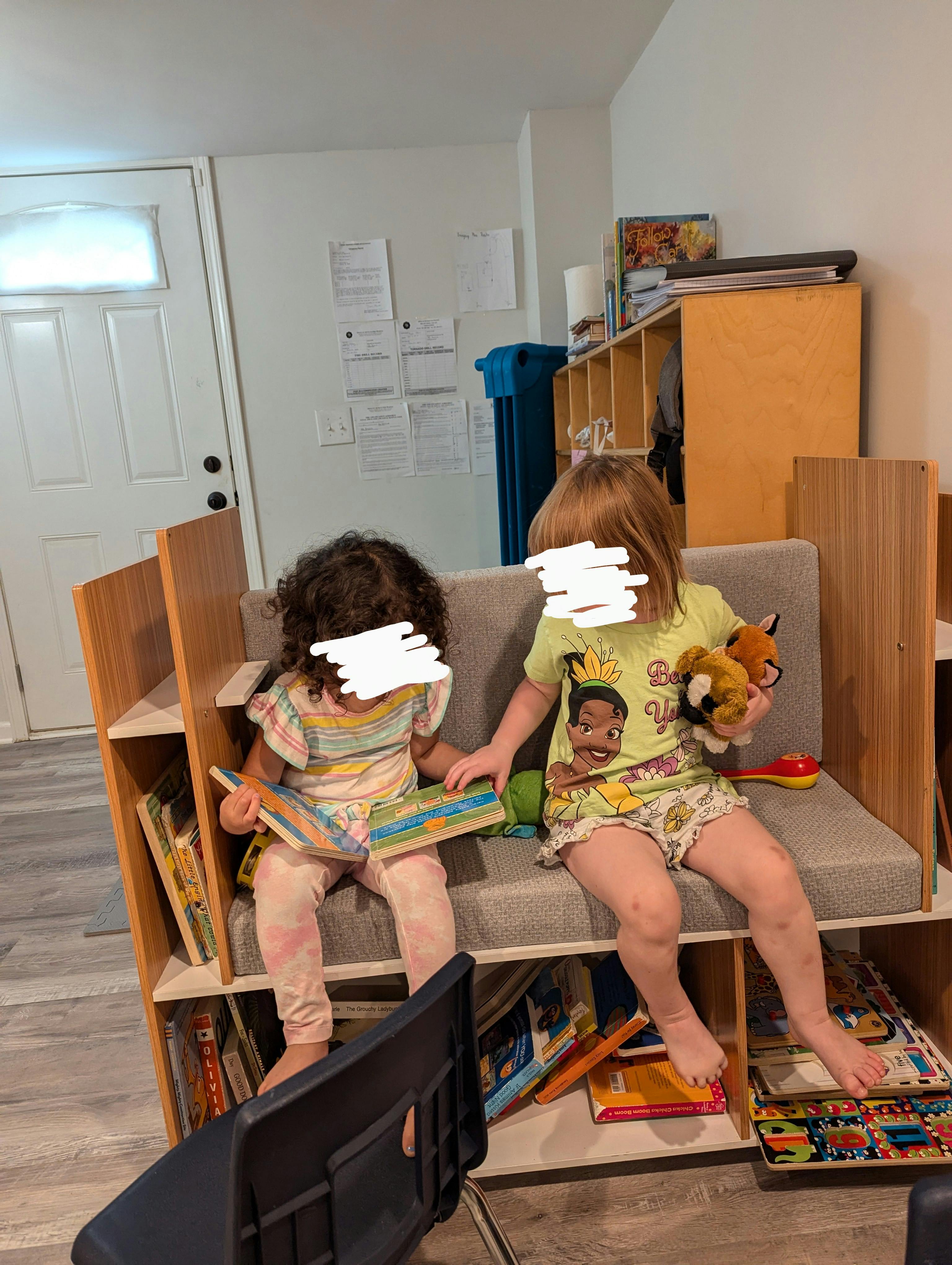 Two children sitting on a bench with books