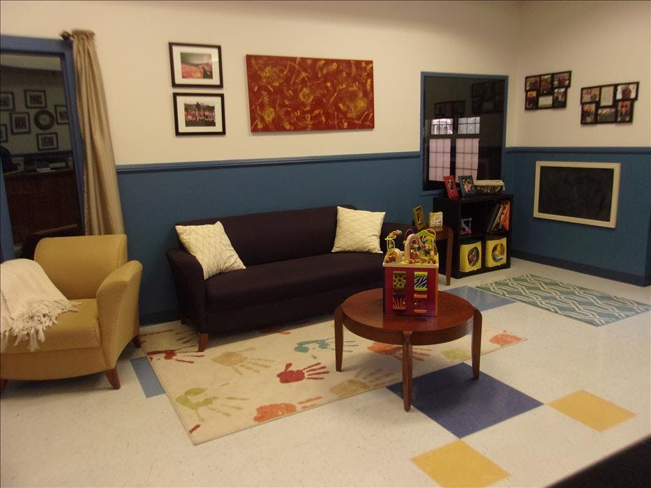 Sofa, armchair, coffee table, and area rugs in a room with paintings and pictures