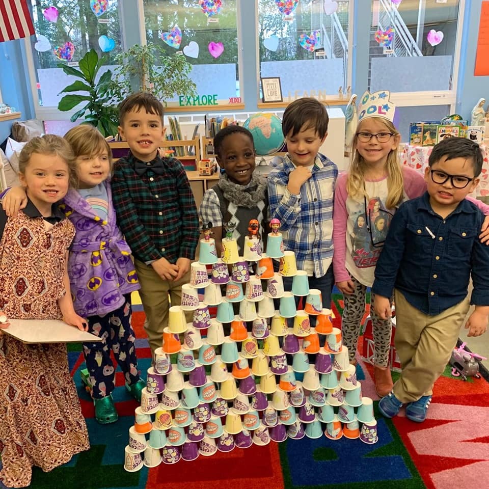 Group of children standing around a pyramid of colorful cups