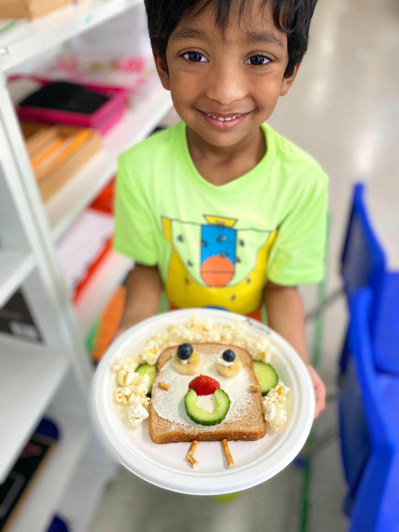 Child holding a plate with toast decorated to look like a face