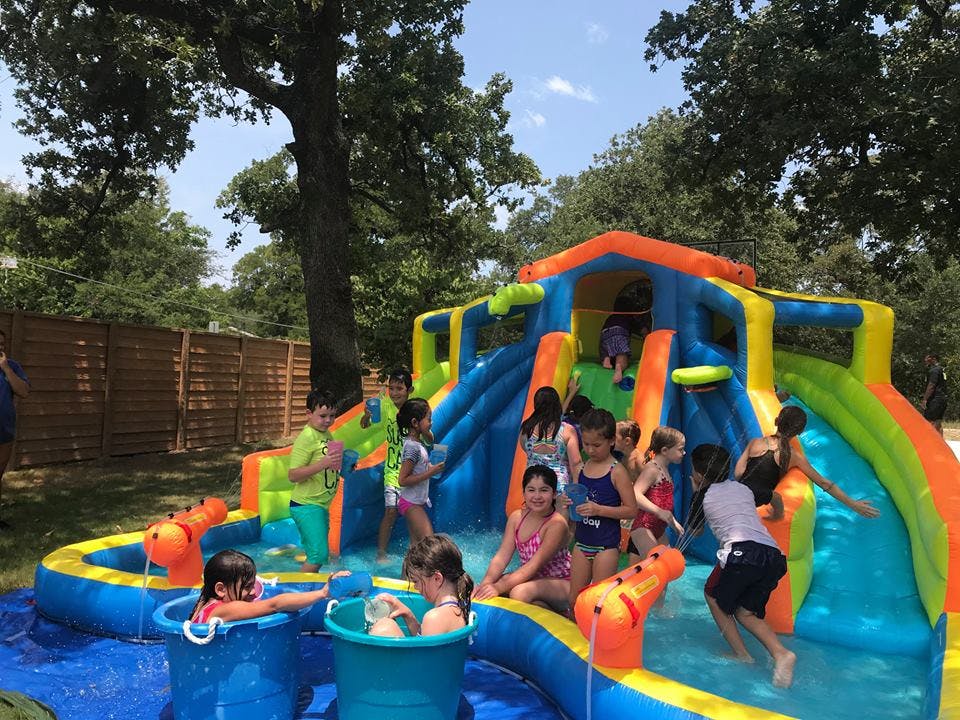 Children playing on a colorful inflatable water slide and pool