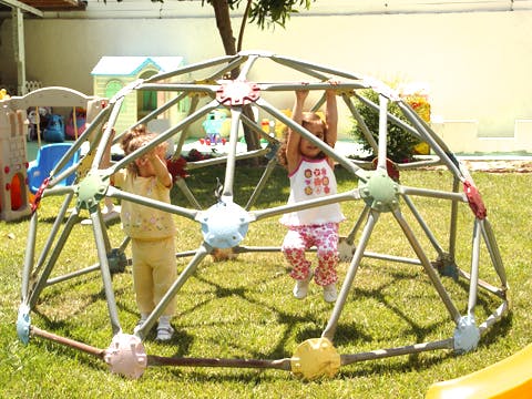 Two children playing on a geodesic dome climber