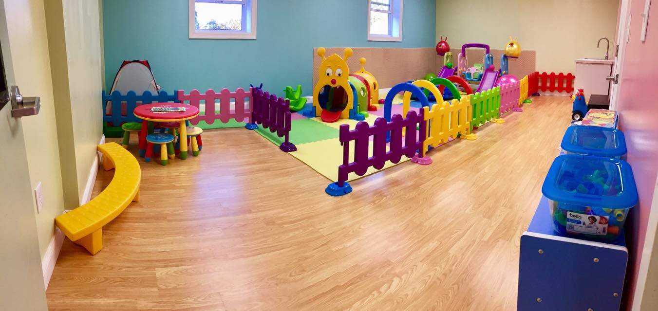 Indoor play area with colorful fences, play structures, and a small table