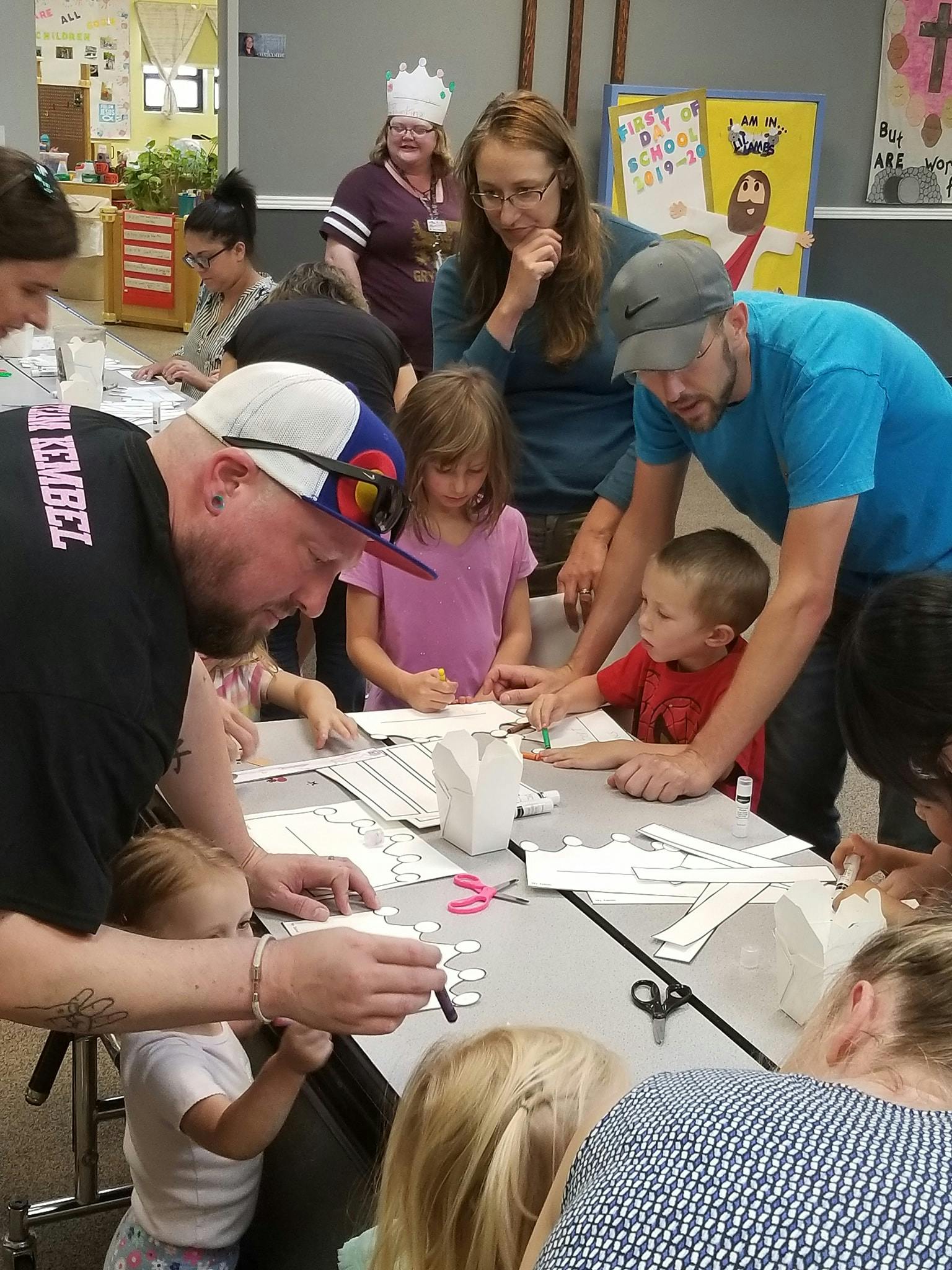 Adults and children gathered around a table doing crafts