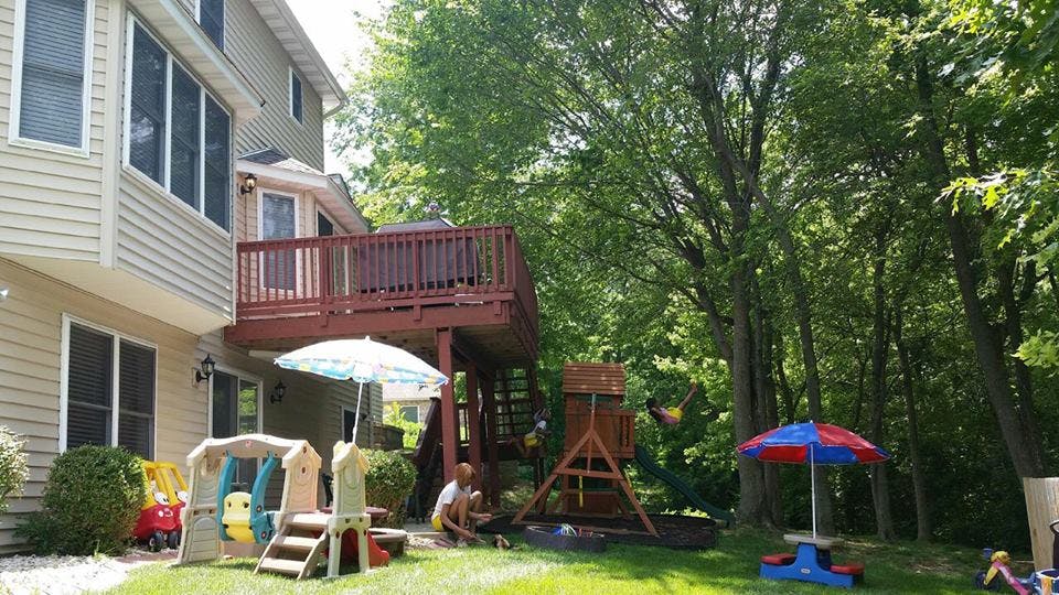 Person kneeling in a yard with a playset and house in the background