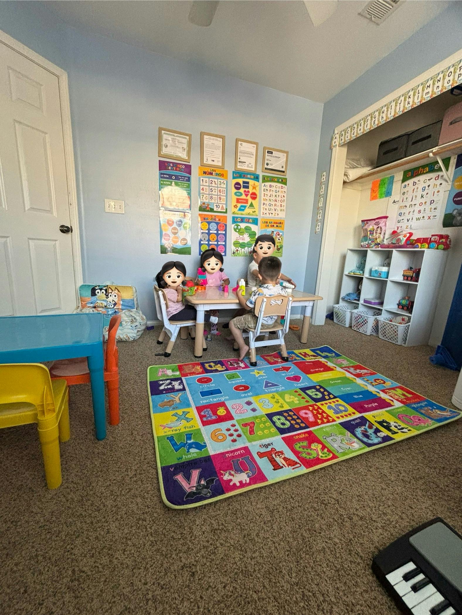 Three children playing at a table in a classroom with educational posters