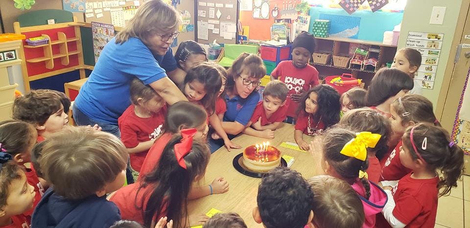 Adults and children gathered around a table with a cake