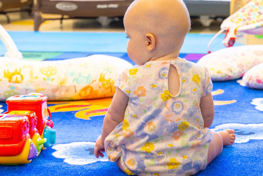 Baby sitting on a colorful rug with toys