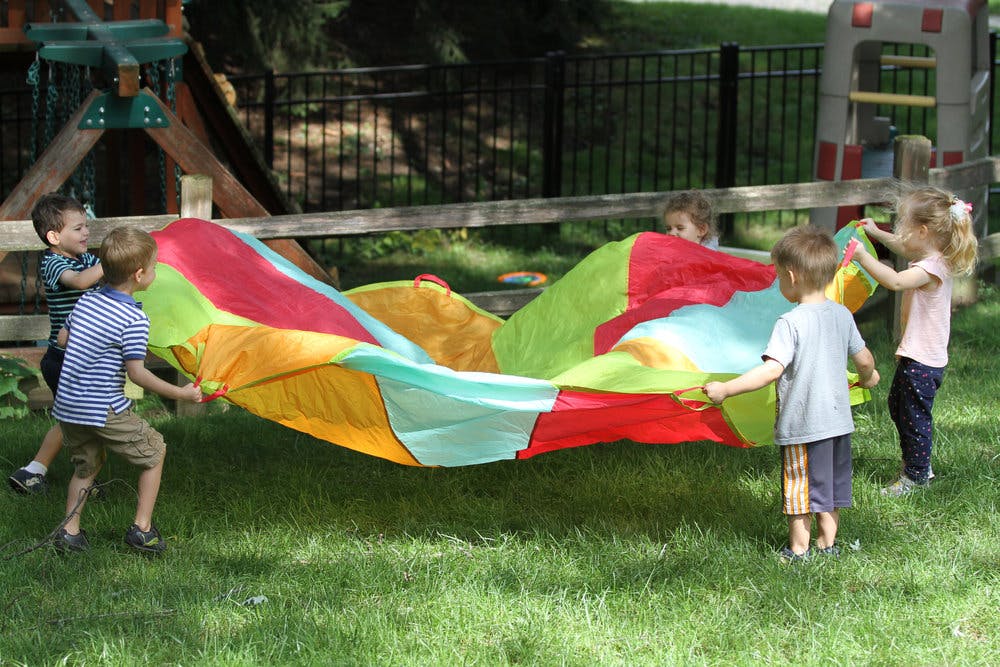 Children playing with a colorful parachute on grass