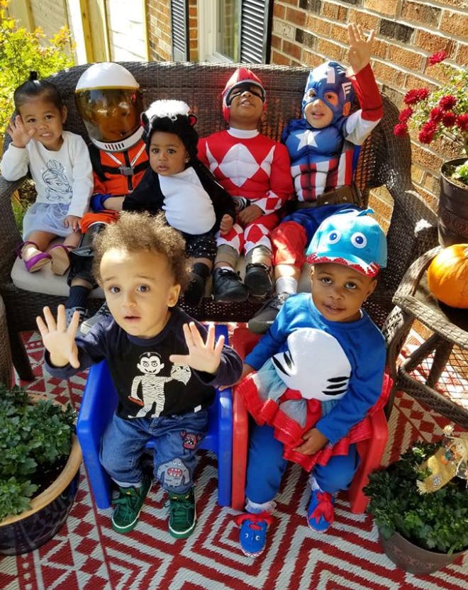 Children in costumes sitting on a bench and in chairs