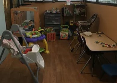 Playroom with baby swing, activity center, and small table with chairs