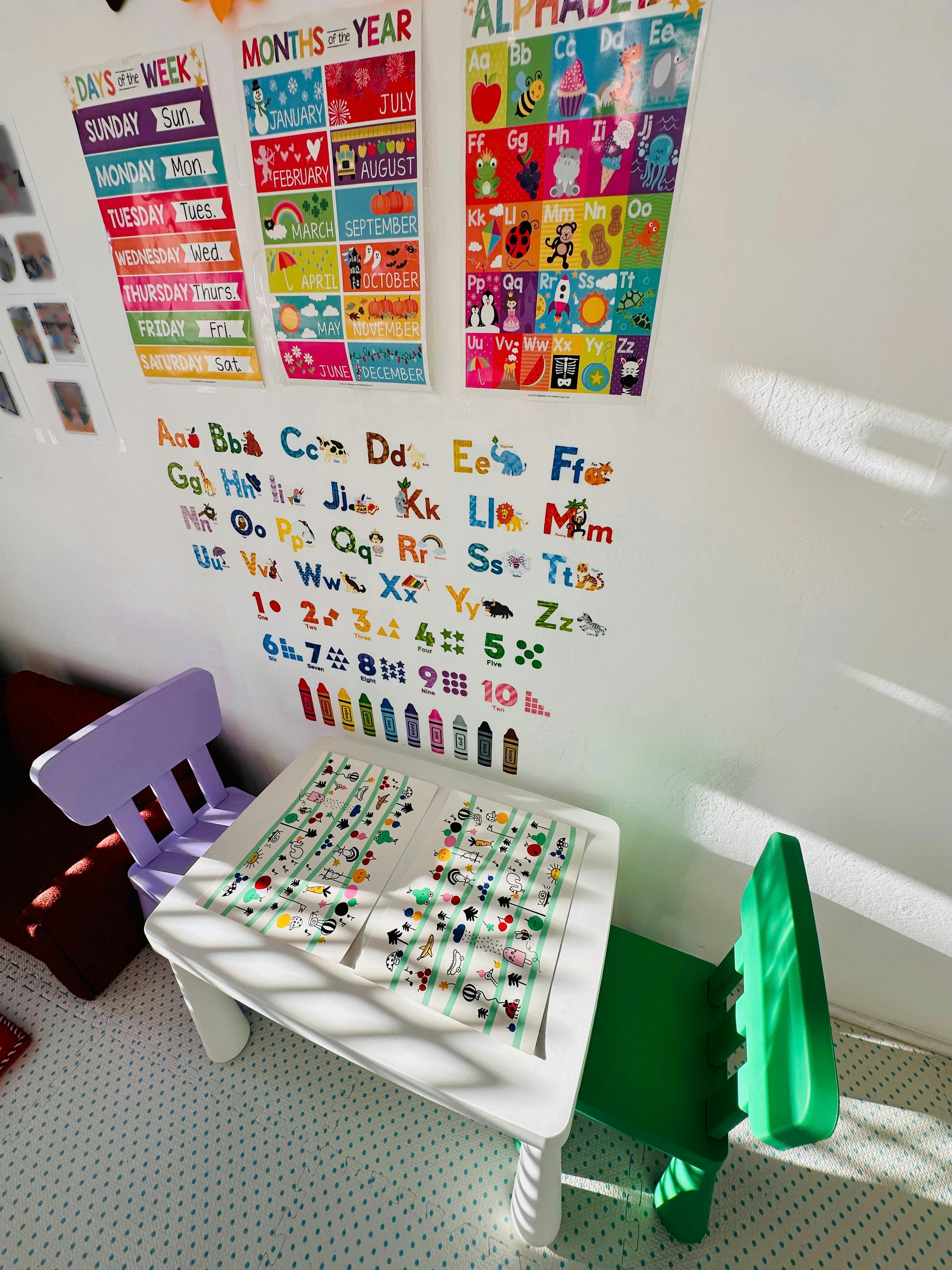 Small table and chairs in a room with educational alphabet and calendar posters