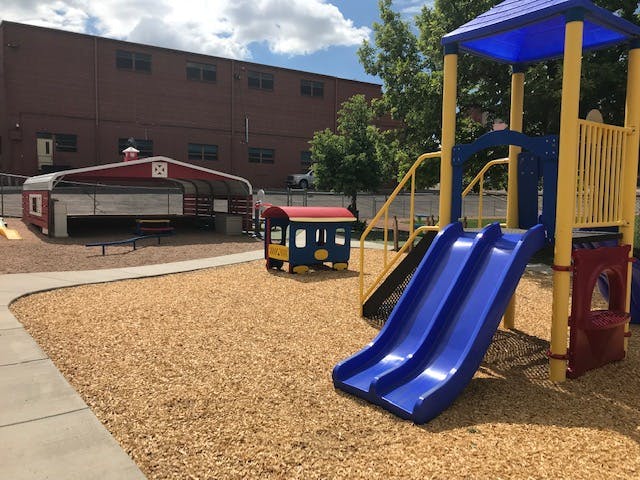 Playground with blue slides, a small train, and a red barn-like structure