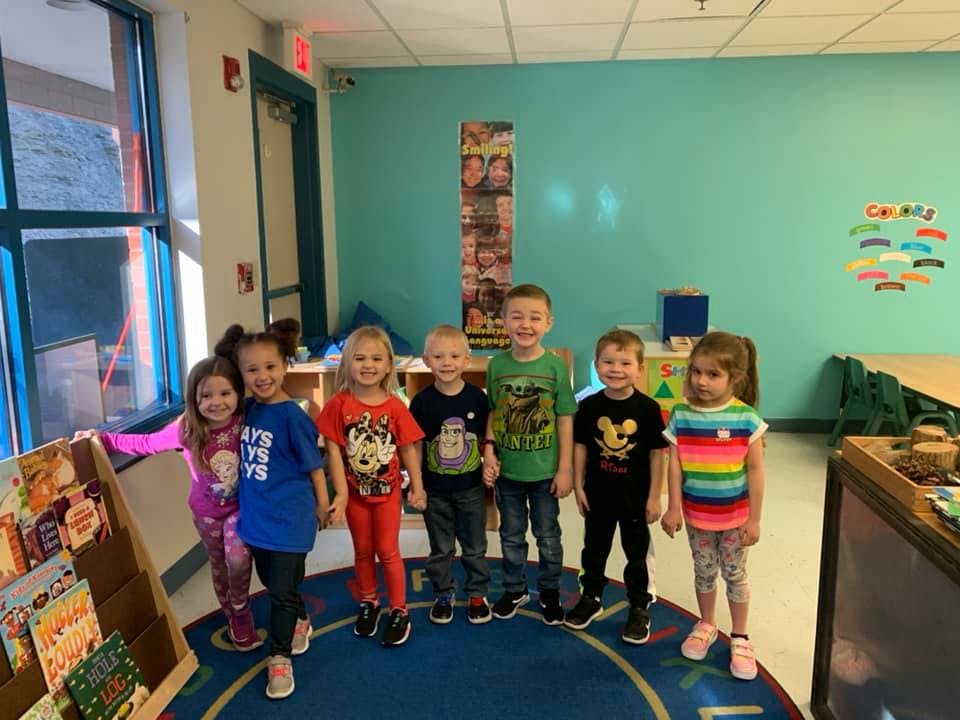 Seven children standing in a classroom
