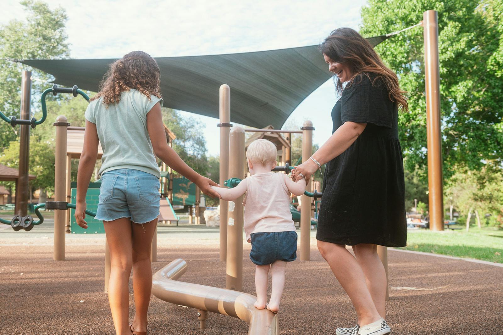 Two people and a child holding hands on playground equipment