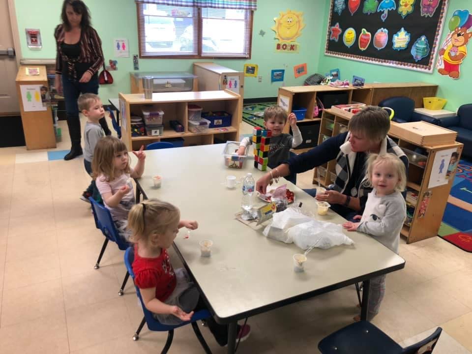 Adult and children sitting at a table in a classroom