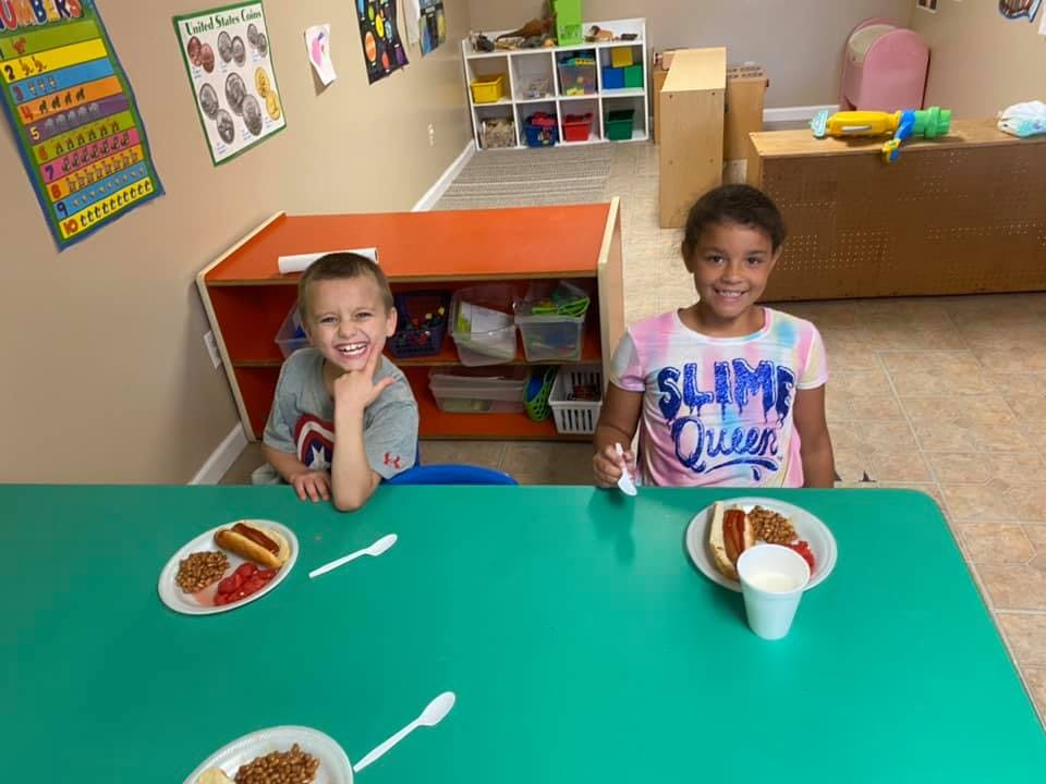 Two children sitting at a table with plates of food